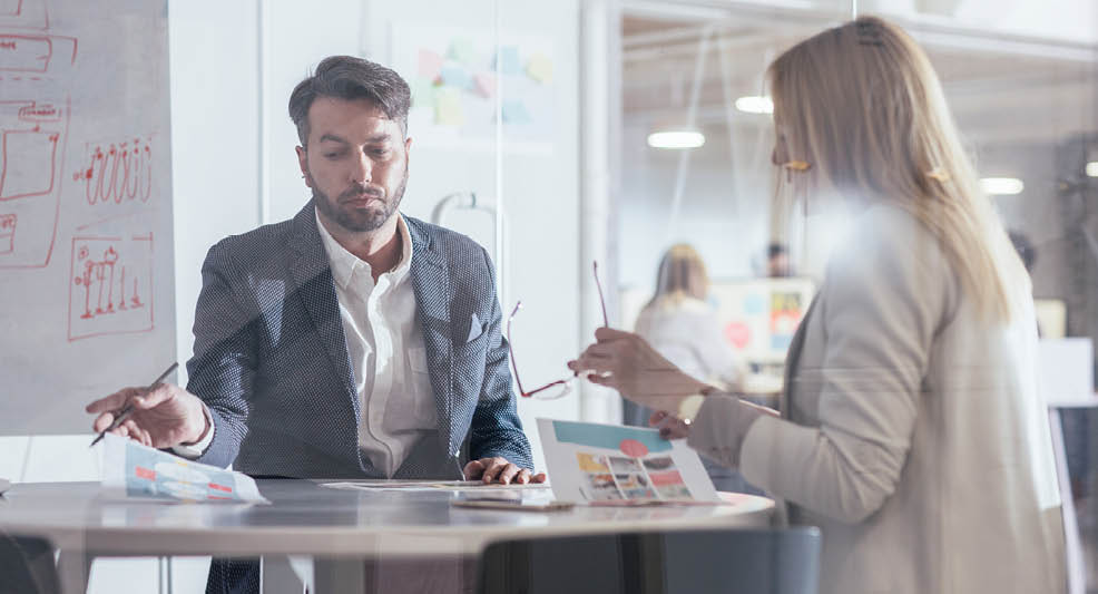 Businessman and businesswoman talking and sitting at meeting room.